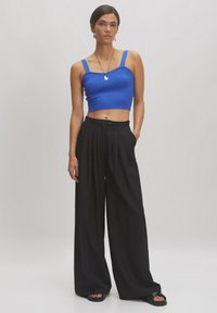 Blauw geribbelde crop top met brede zwarte geplooide broek. De outfit heeft smalle bandjes en instap zwarte sandalen. Eenvoudig ontwerp; geen patronen.