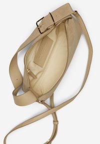 Beige Lederhandtasche mit glattem Äußeren, verstellbarem Riemen, Reißverschlussfach und einem weichen, gefütterten Innenraum mit Markenlabel.