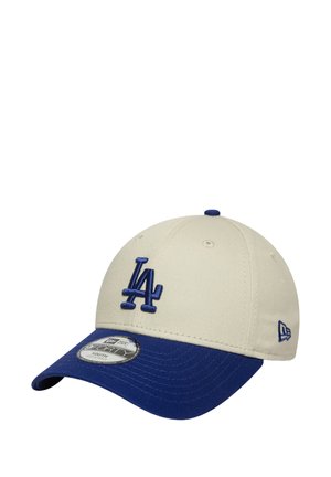 Cappellino da baseball in tessuto beige con visiera blu. Presenta il logo "LA" ricamato in blu sulla parte anteriore. Include un'etichetta sulla parte inferiore della visiera.