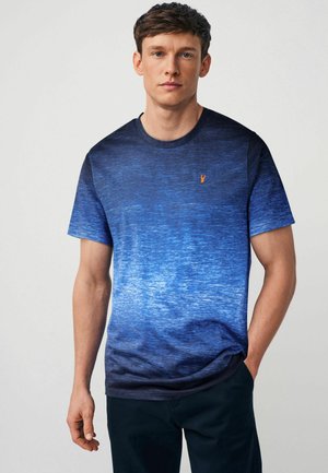 Kortærmet T-shirt i gradient blå med tekstureret mønster. Har et lille orange logo på brystet. Let materiale og afslappet pasform.