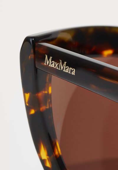 Lunettes de soleil écaille de tortue avec une monture carrée, présentant des verres marron et un logo doré "MaxMara" sur la branche. Fini brillant, texture lisse.