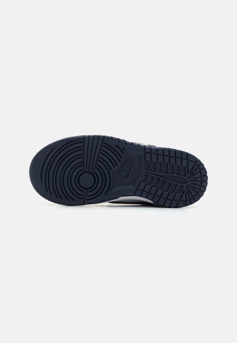 Semelle de sneaker en caoutchouc bleu marine foncé avec des motifs de relief circulaires et linéaires. Présente un logo circulaire au centre et des zones de préhension texturées.