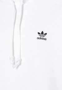 Felpa bianca in cotone con tasca a marsupio, cordini e logo Adidas nero ricamato sul petto, caratterizzata da un classico design a tre strisce.