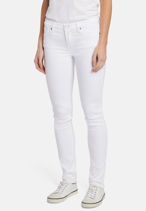 Witte denim jeans met een slim fit, voorzien van voorzakken, een standaard tailleband en subtiele stikseldetails. Gekleed met witte sneakers.