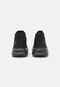 Zwarte sportieve schoenen met een sokachtige uitstraling, textuur bovenkant en een dikke zool. Voorzien van een achterste trekstrip voor gemakkelijk aantrekken.