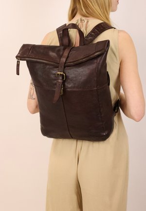 Brauner Leder-Rucksack mit Roll-Top-Design, Messingbeschlägen und verstellbaren Trägern, der eine glatte Textur und ein dezentes Logodesign aufweist.