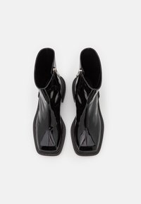 Schwarze Lackleder-Stiefeletten mit einem eleganten Design, spitzen Zehen und strukturierten Seitendetails; mit einem Seitenreißverschluss zum Verschließen.