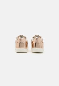 Metallic rose gold sneakers with a smooth finish, padded collar, and white rubber sole. Displayed from the back.