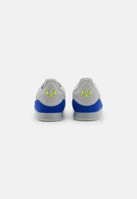 Sneaker grigi con accenti blu, realizzati in un tessuto testurizzato, a forma arrotondata e con vivaci dettagli gialli vicino al tallone.
