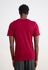 Camiseta de algodón roja de manga corta con un corte relajado, cuello redondo y textura suave, con dobladillo recto y sin gráficos ni adornos.