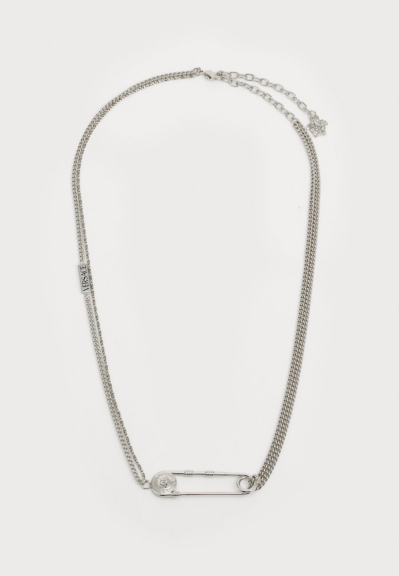 Ασημί τόνος κολιέ που διαθέτει δύο αλυσίδες, μία επίπεδη και μία στριφτή, με μια μεγάλη ασφάλεια και ένα κυκλικό pendant ως αξεσουάρ.