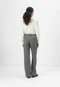 Gray pinstriped trousers with a relaxed fit. Features a waistband with belt loops and two back pockets. Pairing with a white striped shirt.