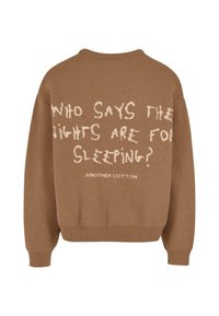 Hnědý pletený svetr se bílým textem na zádech: "KDO ŘÍKÁ, ŽE NOCI JSOU NA SPANÍ?" a štítek "ANOTHER COTTON".