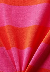 Tissu tricoté avec des larges rayures horizontales alternées en rose vif et orange, montrant une texture douce et de légers plis.
