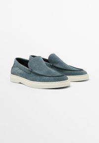 Šedohnědé semišové slip-on boty s kulatou špičkou, bílou gumovou podrážkou a minimalním prošíváním na svršku.