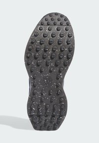 Czarna gumowa podeszwa buta z fakturowaną powierzchnią o okrągłych i sześciokątnych wzorach, zaprojektowana dla zapewnienia przyczepności i stabilności.