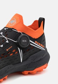 Scarpe da escursionismo nere e arancioni con tomaia testurizzata, sistema di allacciatura Boa e suola robusta con tasselli multi-direzionali.