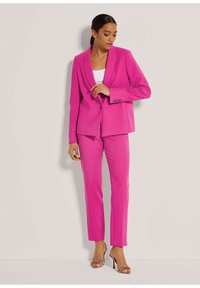 Rosa maßgeschneiderter Anzug, bestehend aus einem Blazer mit aufgesetztem Revers und passenden Slim-Fit-Hosen, gefertigt aus einem glatten Stoff.