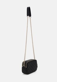 Borsa a tracolla nera trapuntata con catena dorata e manico superiore in pelle. Presenta una chiusura con zip e una forma rettangolare.