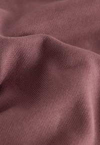 Pehme, lavendlivärvi kootud kangas nähtava peene soonilise tekstuuri ja õrnade voldikutega, mis loovad varje ja helkeid.