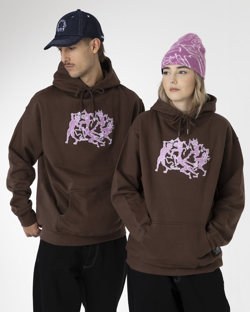 Sudaderas marrones con un diseño gráfico rosa, con un bolsillo frontal, combinadas con un gorro rosa con patrón y una gorra azul marino.