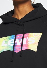 Felpa nera con cappuccio e logo Levi's in tie-dye dai colori vivaci. Presenta un cappuccio, coulisse e tessuto testurizzato.