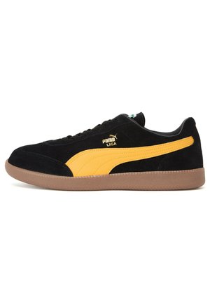 Sort ruskind sneakers med gule ruskindsdetaljer og en gummirubber sål. Har et lille logo på siden og klassisk snørebåndsdesign.