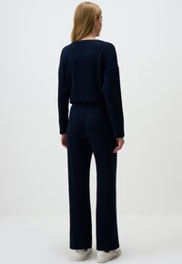 Navy knit two-piece outfit featuring a relaxed fit sweater with long sleeves and matching wide-leg pants, textured fabric, and elastic waistband.