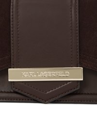 Braune Leder- und Wildleder-Handtasche mit einer goldfarbenen Hardware-Plakette, auf der "KARL LAGERFELD" eingraviert ist, was einen eleganten Akzent setzt.