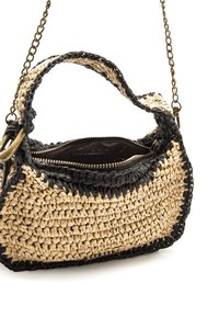 Pequeño bolso de mano tejido de paja con ribete negro, cremallera superior parcialmente abierta y delgada cadena dorada como correa para el hombro sobre fondo blanco.