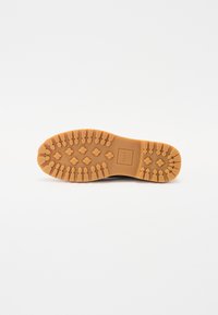 Brown rubber outsole with a zigzag pattern and hexagonal shapes, featuring the brand name "CLAE" embossed at the center.