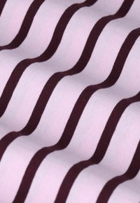 Tissu rose avec une texture lisse, présentant des rayures horizontales marron foncé, créant un motif ondulé à la surface.