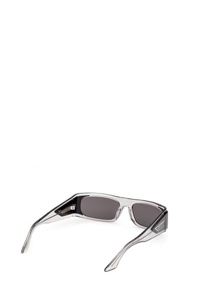 Gafas de sol rectangulares transparentes de color gris con lentes oscuras y varillas gruesas, abiertas, sobre un fondo blanco.