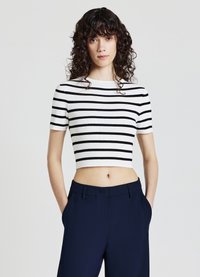 Top corto a maniche corte a righe bianche e nere, realizzato in materiale a coste. Abbinato a pantaloni blu scuro a vita alta.