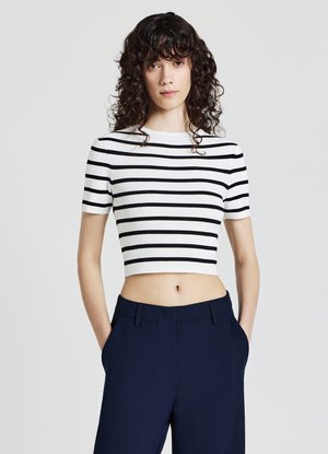 Top corto a maniche corte a righe bianche e nere, realizzato in materiale a coste. Abbinato a pantaloni blu scuro a vita alta.