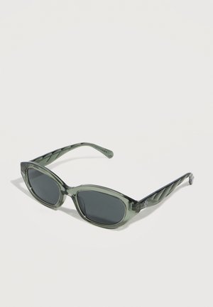 Translucent gray oval sunglasses with dark lenses and subtly twisted temples resting on a light surface.