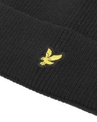 Svart ribbad mössa gjord av mjukt stickat tyg, med en gul broderad örnlogotyp framtill.