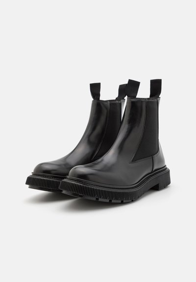 Black leather Chelsea boots featuring elastic side panels, pull tabs, and a chunky rubber sole with a ribbed texture.