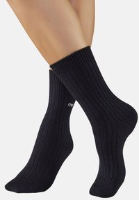 Ribbed black socks with a thick cuff, made of a soft textile, featuring subtle brand lettering near the ankle.