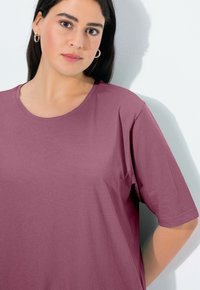 T-shirt di cotone rosa polveroso con maniche corte, scollatura tonda e texture morbida, caratterizzato da una vestibilità rilassata e dettagli di cucitura minimi.