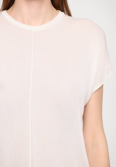 Light beige knit t-shirt with a crew neckline, short sleeves, and a subtle seam detail down the center, featuring a soft texture.