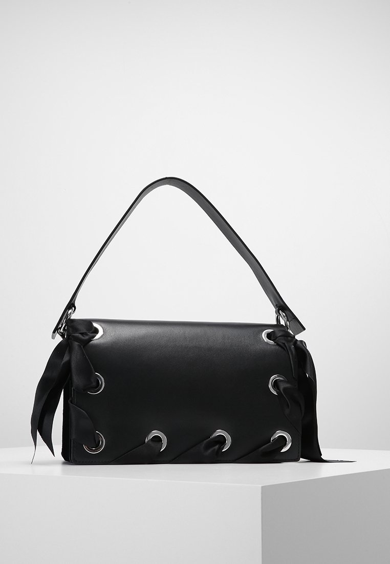 Černá kožená kabelka s hladkým povrchem, s kovovými očky a saténovými akcenty na bocích. Jediný plochý ramenní popruh.