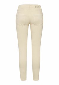 Jeans ajustados de color beige con una textura suave, diseño de cinco bolsillos y un sutil bordado en los bolsillos traseros. Presentan una cinturilla de altura media.