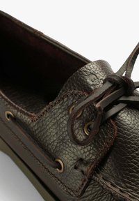 Braune Lederbootsschuhe mit strukturierter Oberfläche, kontrastierenden Nähten und bronzenen Ösen. Sie haben eine abgerundete Spitze und Schnürdetails.