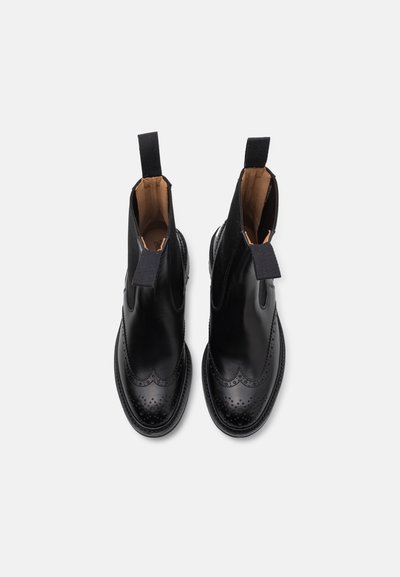 Bocanci din piele neagră până la gleznă, cu vârf rotund, panouri laterale elastice și detalii decorative brogue de-a lungul vârfului și marginii superioare.
