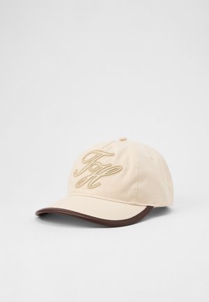 Beige baseball cap with brown brim edge and embroidered stylized initials on front, displayed on a plain white background.