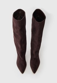 Knee-high, dark brown suede boots with pointed toes and slouchy design. Smooth texture and a structured, folded opening at the top.