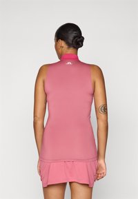 Vestido rosa sem mangas com colarinho alto e saia em camadas. Feito de material elástico, apresentando um logótipo nas costas. Textura suave.