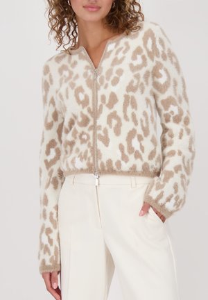 Flauschiger Reißverschluss-Pullover in Creme mit beigefarbenem Leopardenmuster. Mit langen Ärmeln und weichem Material, kombiniert mit weißen Hosen.