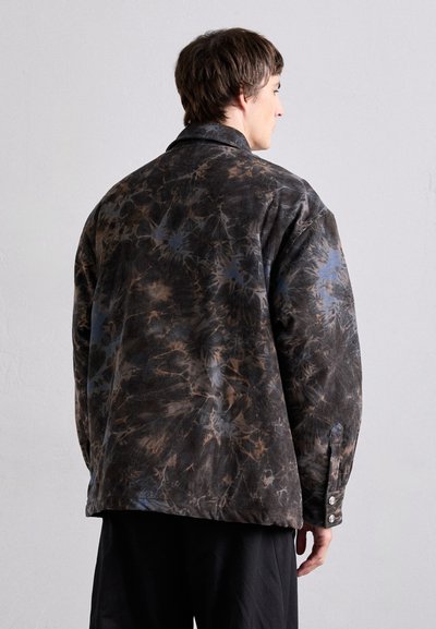Oversized jacket in dark brown, featuring a tie-dye pattern with blue accents. Made from textured fabric, with a notched collar and button cuffs.